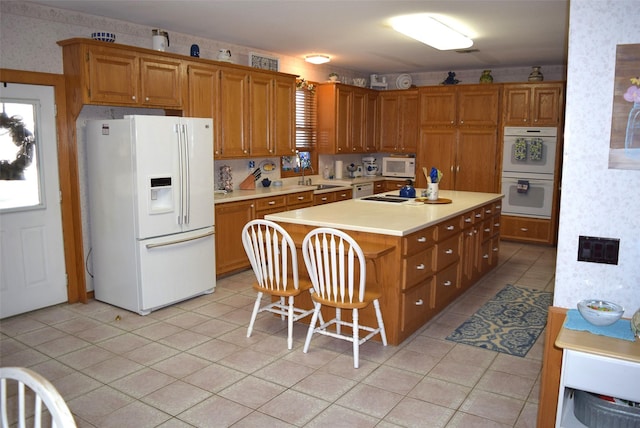 kitchen with a kitchen bar, a center island, white appliances, and sink