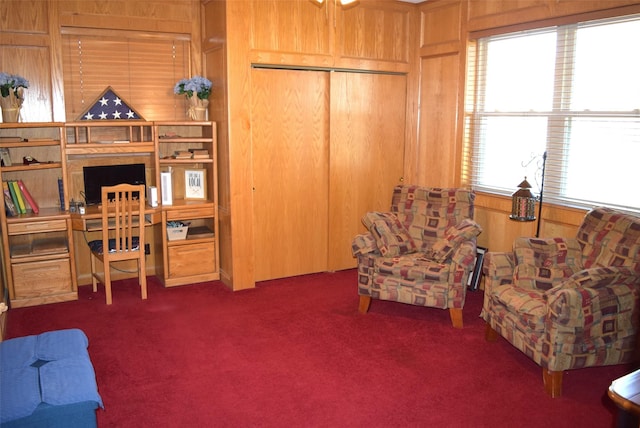 sitting room featuring dark colored carpet and wooden walls