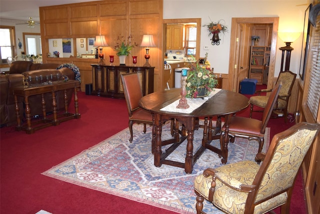 dining space featuring ceiling fan, carpet, and wood walls