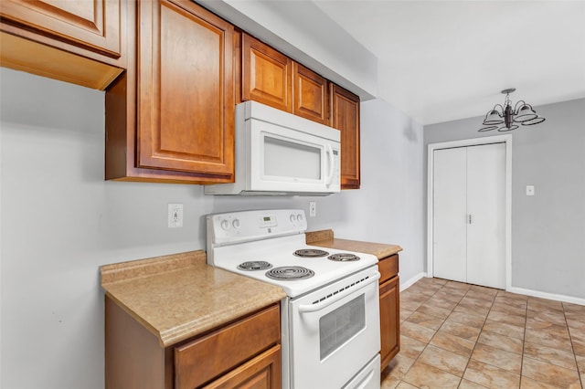 kitchen with pendant lighting, white appliances, and a chandelier