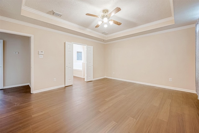 unfurnished room with a textured ceiling, wood finished floors, a ceiling fan, baseboards, and a raised ceiling