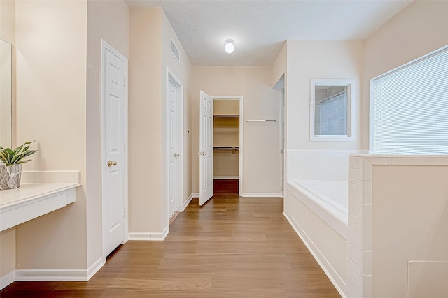 hall with light wood-type flooring, baseboards, and visible vents