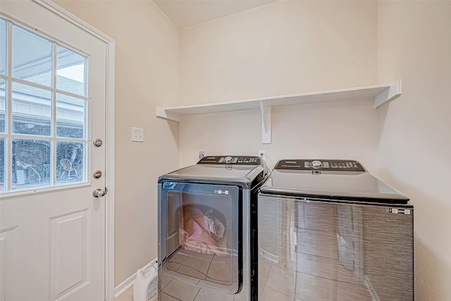 clothes washing area with laundry area, light tile patterned floors, baseboards, and separate washer and dryer