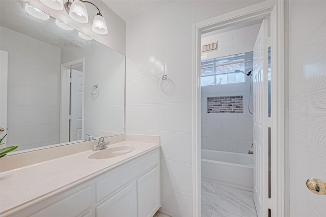 full bath with  shower combination, marble finish floor, tile walls, and vanity