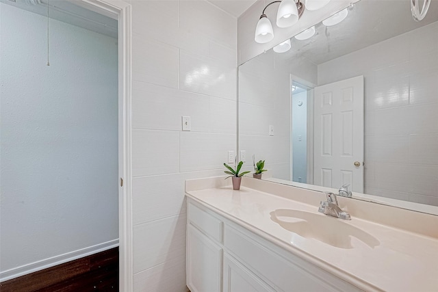 bathroom featuring baseboards, tile walls, and vanity