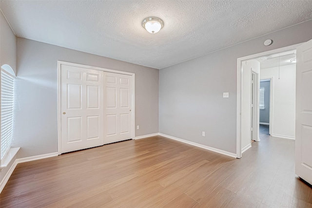 unfurnished bedroom featuring attic access, light wood-type flooring, a closet, and baseboards