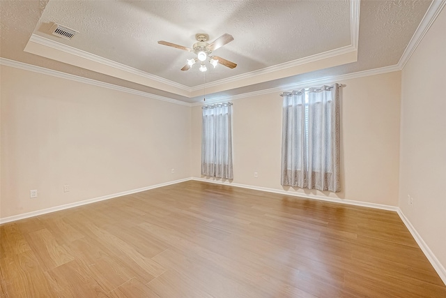 spare room with a tray ceiling, crown molding, a ceiling fan, a textured ceiling, and wood finished floors