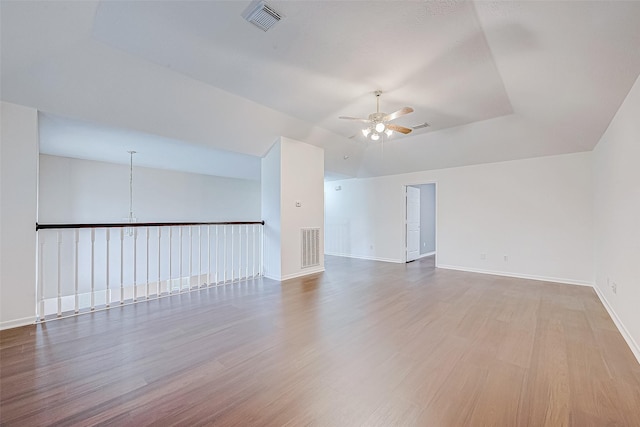 spare room featuring baseboards, visible vents, ceiling fan, wood finished floors, and vaulted ceiling