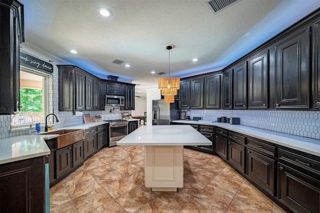 kitchen featuring pendant lighting, a center island, sink, appliances with stainless steel finishes, and tasteful backsplash