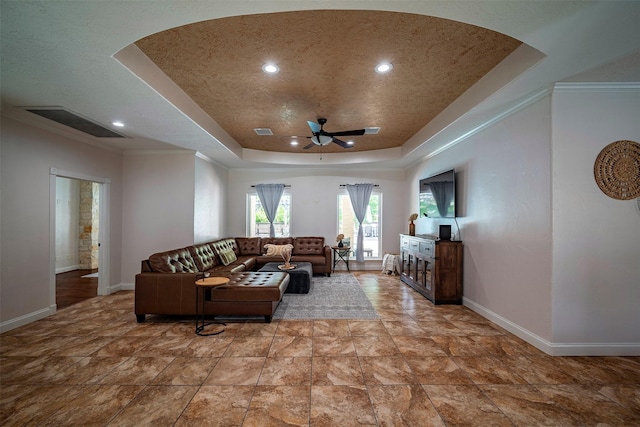 living room featuring a tray ceiling, ceiling fan, and crown molding