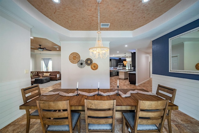 dining area with a raised ceiling, ceiling fan with notable chandelier, and ornamental molding