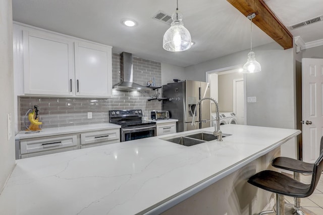 kitchen with stainless steel appliances, wall chimney range hood, beam ceiling, pendant lighting, and white cabinets