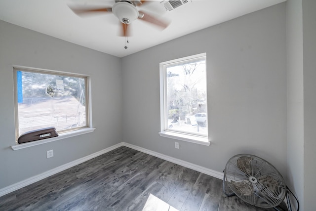 spare room with dark hardwood / wood-style flooring, ceiling fan, and plenty of natural light