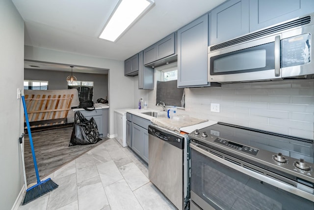 kitchen with backsplash, stainless steel appliances, gray cabinetry, and sink