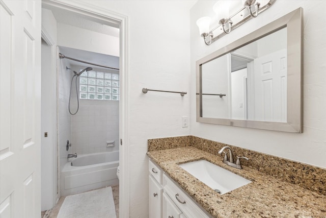 full bathroom featuring vanity, tiled shower / bath combo, and toilet