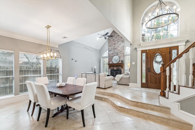 dining room featuring a fireplace, ceiling fan with notable chandelier, and high vaulted ceiling