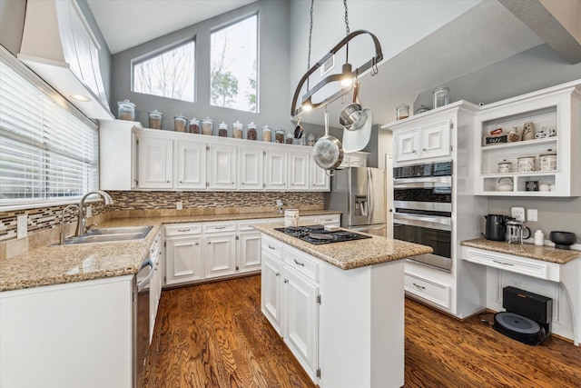 kitchen featuring light stone counters, stainless steel appliances, sink, white cabinetry, and a kitchen island