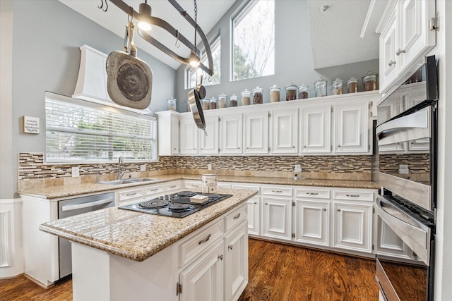 kitchen featuring a center island, lofted ceiling, white cabinets, sink, and black stovetop