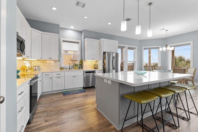 kitchen with white cabinets, a breakfast bar, a center island, and appliances with stainless steel finishes