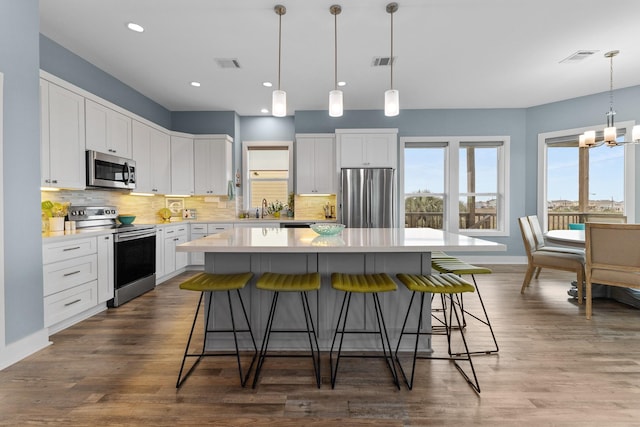 kitchen featuring pendant lighting, a center island, white cabinetry, and stainless steel appliances