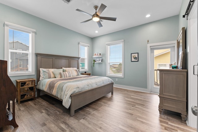 bedroom featuring hardwood / wood-style flooring, ceiling fan, and a barn door