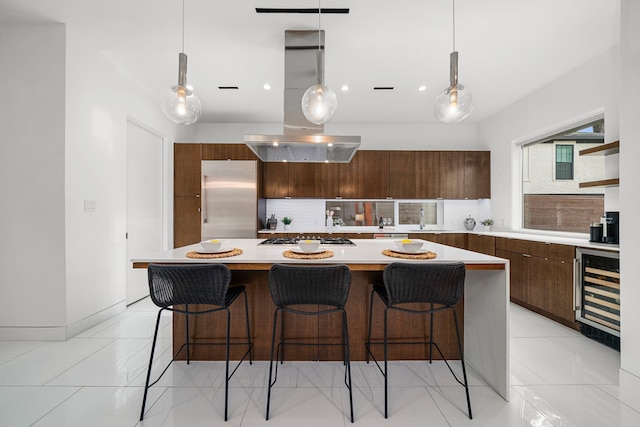 kitchen featuring stainless steel appliances, decorative light fixtures, a center island, and wine cooler