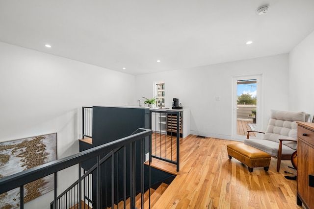 living area with light wood-type flooring, beverage cooler, and sink