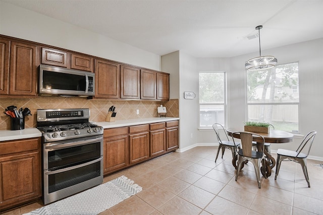 kitchen featuring decorative backsplash, light tile patterned floors, appliances with stainless steel finishes, decorative light fixtures, and a chandelier