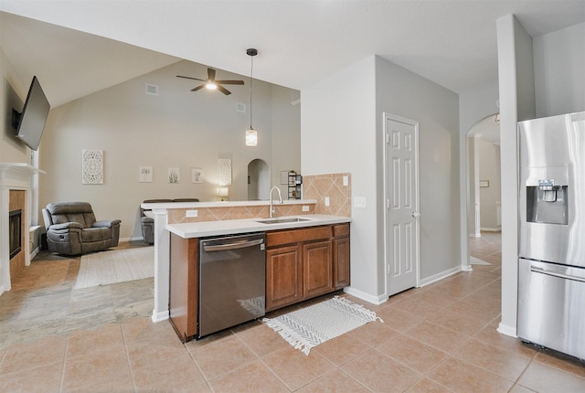 kitchen featuring backsplash, stainless steel appliances, ceiling fan, sink, and a fireplace