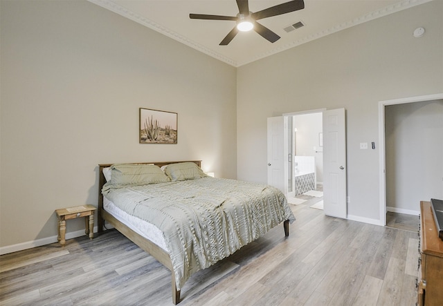 bedroom featuring ensuite bath, ceiling fan, light hardwood / wood-style floors, and a high ceiling