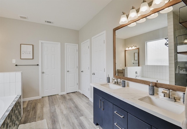 bathroom with plus walk in shower, vanity, and hardwood / wood-style flooring