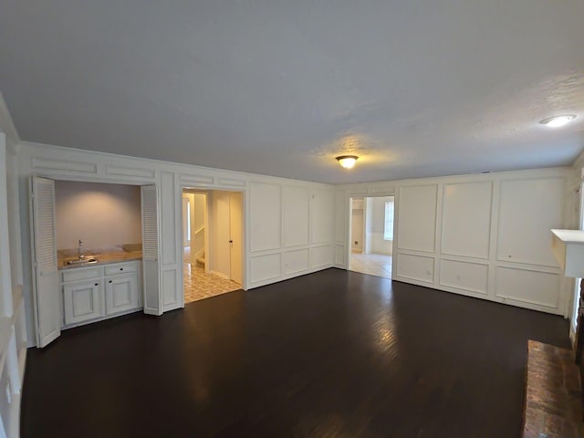 unfurnished living room featuring dark hardwood / wood-style flooring and sink