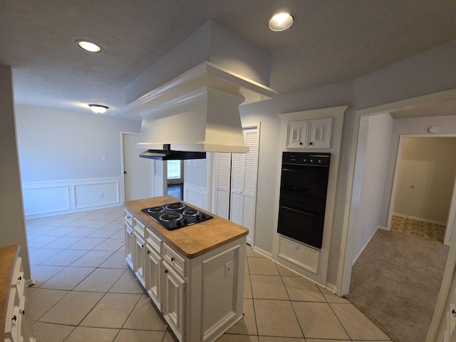 kitchen featuring a center island, white cabinets, wooden counters, light tile patterned flooring, and black appliances