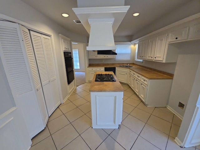 kitchen with white cabinets, custom exhaust hood, a center island, and black appliances