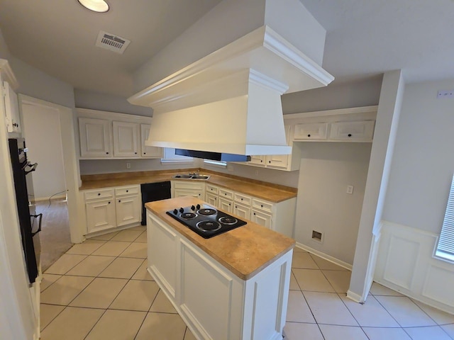 kitchen with light tile patterned flooring, a center island, white cabinets, and black appliances