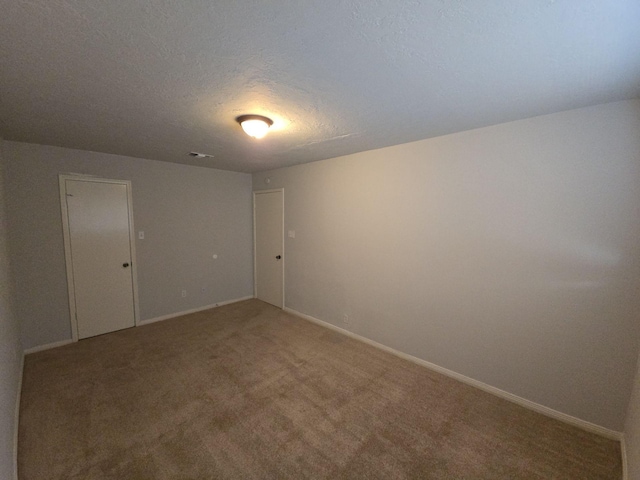 spare room with carpet flooring and a textured ceiling