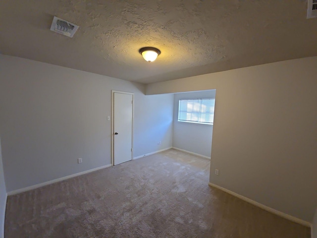 spare room featuring carpet floors and a textured ceiling