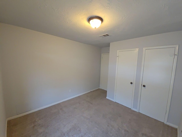 unfurnished bedroom with a textured ceiling and light carpet