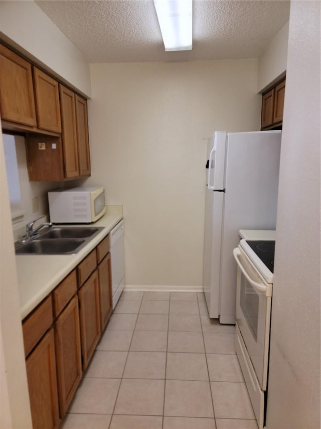 kitchen with a textured ceiling, white appliances, sink, and light tile patterned floors