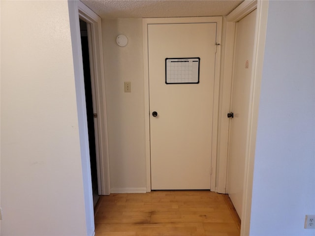 hall featuring a textured ceiling and light wood-type flooring