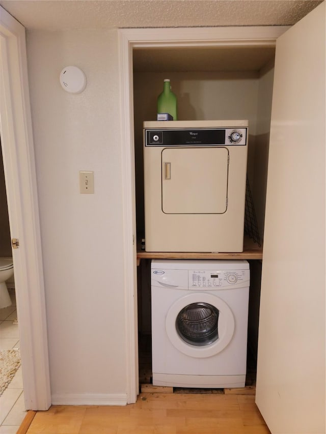 laundry area with stacked washer / dryer and light hardwood / wood-style floors