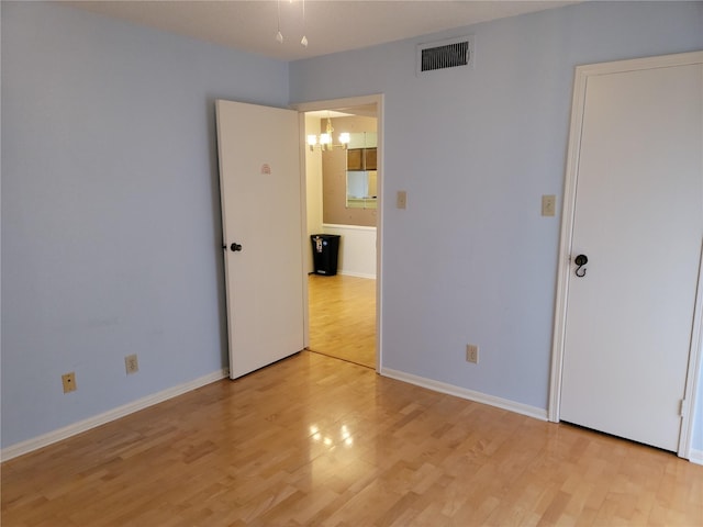 empty room with an inviting chandelier and light wood-type flooring