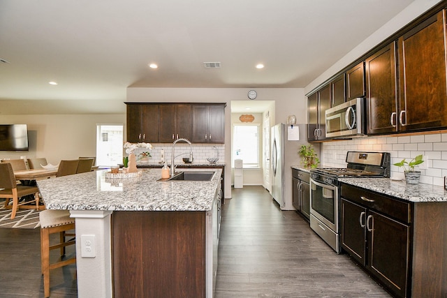 kitchen featuring sink, stainless steel appliances, a kitchen breakfast bar, dark hardwood / wood-style flooring, and a kitchen island with sink