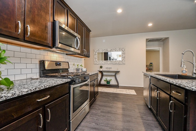 kitchen with sink, decorative backsplash, dark hardwood / wood-style floors, appliances with stainless steel finishes, and light stone counters