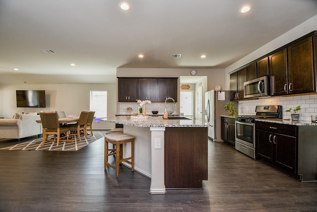 kitchen featuring appliances with stainless steel finishes, dark hardwood / wood-style floors, a kitchen island with sink, and sink