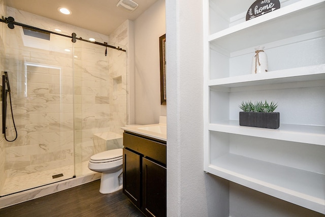 bathroom featuring built in shelves, an enclosed shower, toilet, vanity, and hardwood / wood-style flooring