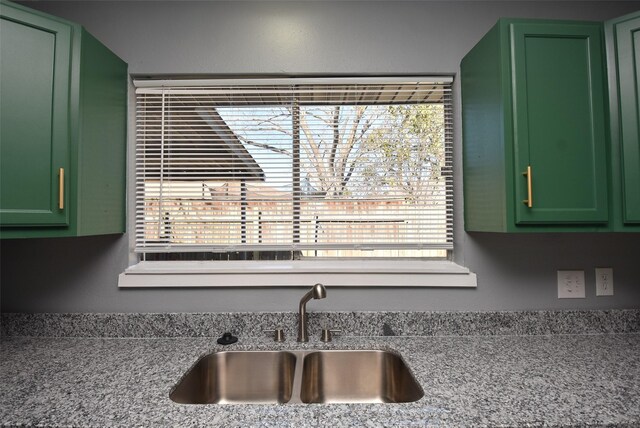 kitchen with light stone countertops, green cabinets, and sink