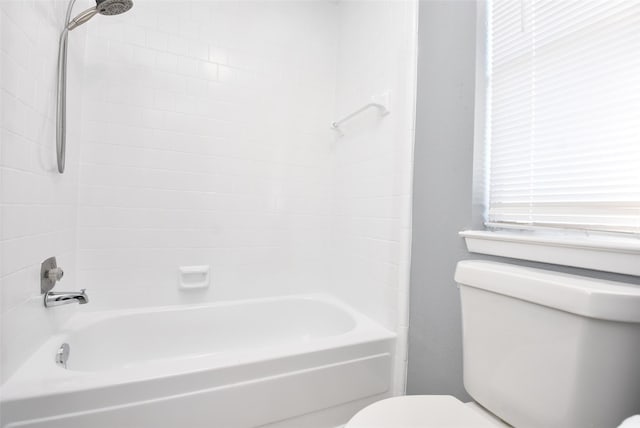 bathroom with tiled shower / bath combo and toilet