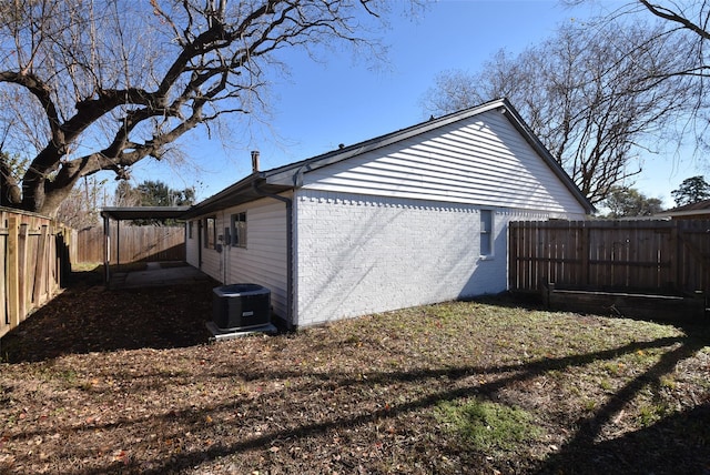 view of home's exterior featuring a fenced backyard, brick siding, and central AC