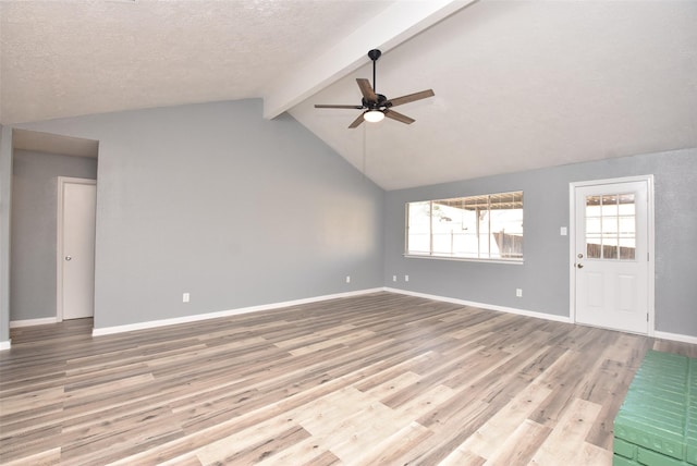 unfurnished living room with lofted ceiling with beams, ceiling fan, light hardwood / wood-style floors, and a textured ceiling